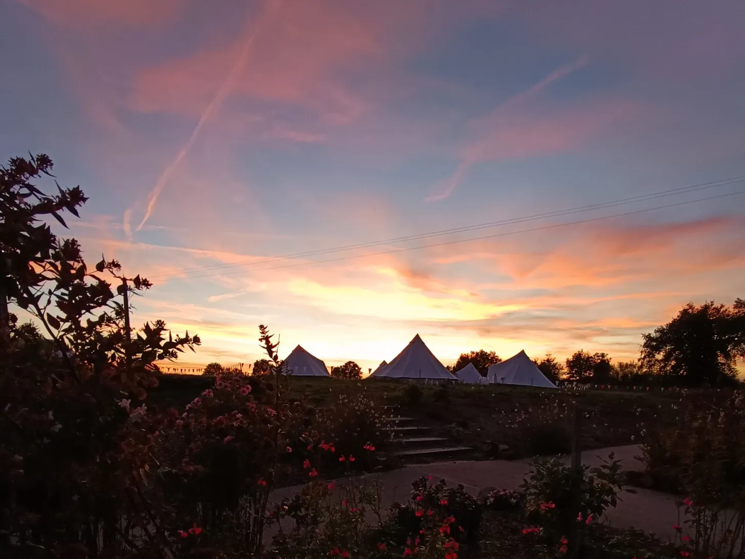 Les tentes du village de tipis sur la crête de la prairie, au coucher du soleil, vues depuis le jardin